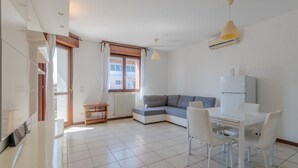 Ein modernes Wohnzimmer mit einer Couch, einem Esstisch, Stühlen und einem Fernseher.