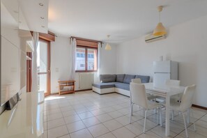 Ein modernes Wohnzimmer mit einer Couch, einem Esstisch, Stühlen und einem Fernseher.