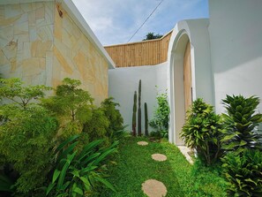 Un patio con paredes de piedra, cerca de madera y diversas plantas.