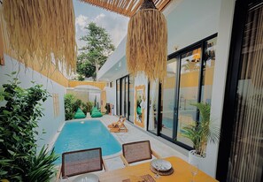 Un área junto a la piscina con una piscina pequeña, sillones de descanso y una mesa con un vaso.