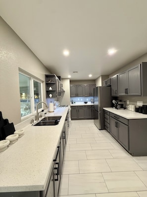 A modern kitchen with grey cabinets, a white countertop, and a window with a view. - House in Las Vegas, NV (North Las Vegas)