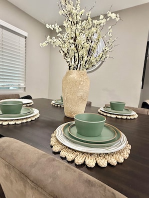 A dining table with a vase of white flowers, green plates, and bowls. - House in Las Vegas, NV (North Las Vegas)