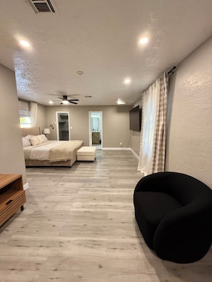 A bedroom with a bed, a chair, a TV, and a door leading to a bathroom. - House in Las Vegas, NV (North Las Vegas)