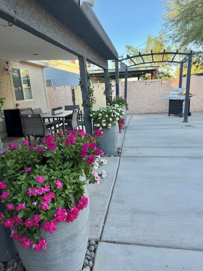An outdoor patio area with seating, a grill, and potted plants. - House in Las Vegas, NV  (North Las Vegas)