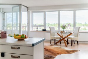 A modern kitchen with a dining area, large windows, and a view of the countryside. - Vacation apartment "FjordHavn" on the 8th floor of the Viking Tower (Schleswig)