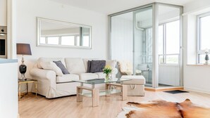 Een moderne woonkamer met een bank, salontafel en glazen deur die leidt naar een balkon.