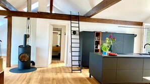 A modern kitchen with a central island, wooden beams, and a visible chimney. - "Hafenpanorama" vacation rental with a view of the Old Town and the harbor, located right in (Flensburg)