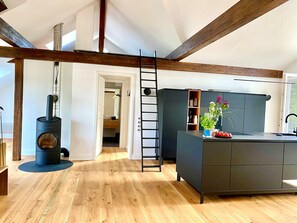 A modern kitchen with a central island, wooden beams, and a visible chimney. - "Hafenpanorama" vacation rental with a view of the Old Town and the harbor, located right in (Flensburg)