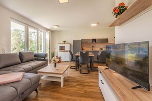 Ein modernes Wohnzimmer mit Sofa, Couchtisch, Fernseher und Essbereich.