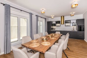 Ein stilvoller Essbereich mit Holztisch, gewebten Platzsets und weißen Stühlen.