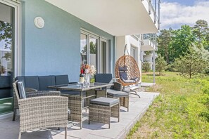Eine Außenpatio mit Korbmöbeln, einem Hängesessel und einem Tisch mit Blumen.