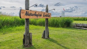 Un panneau indicateur en bois portant l’inscription « Naturschutzgebiet Loddin » dans un environnement naturel.