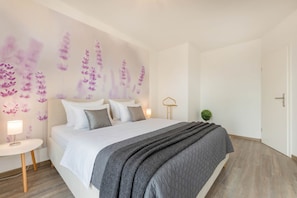 A bedroom with a bed, bedside table, wall art, and a door. - Modern vacation home with lake view, terrace & barbecue in Loddin (Loddin)