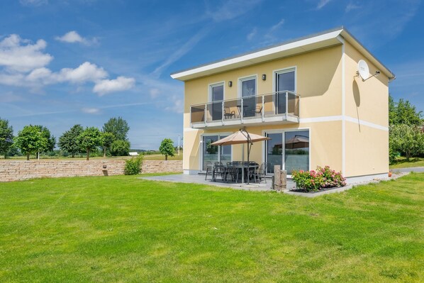 Un bâtiment à deux étages doté d’un balcon, d’un espace extérieur aménagé pour s’asseoir et d’un jardin.