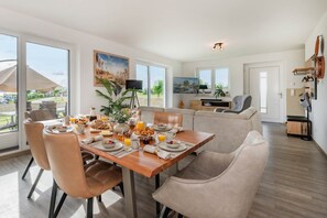 A dining area with a table set for breakfast, a sofa, and a TV in the background.