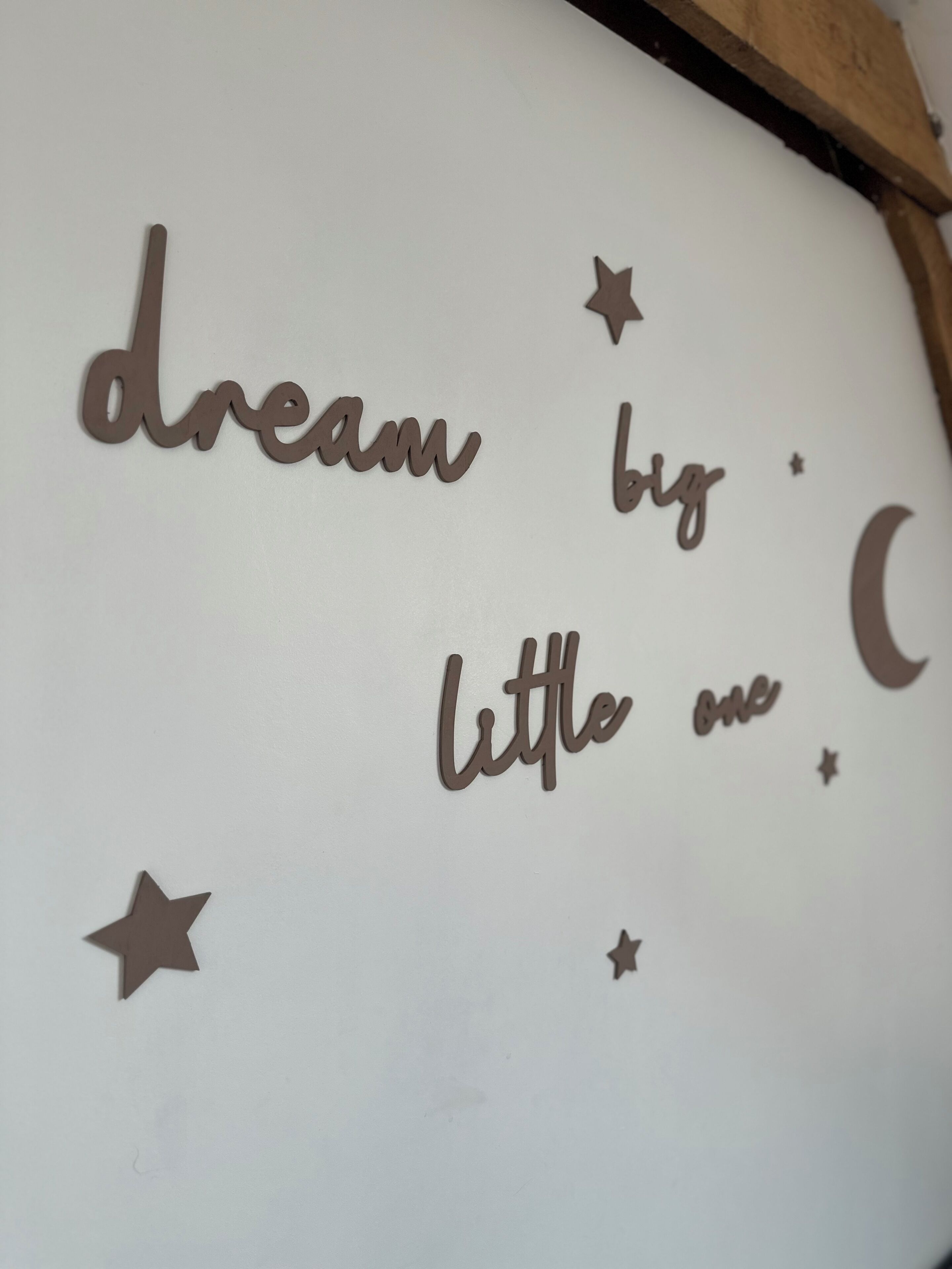 Un muro con una frase decorativa, 'dream big little me', e forme di stelle e luna.