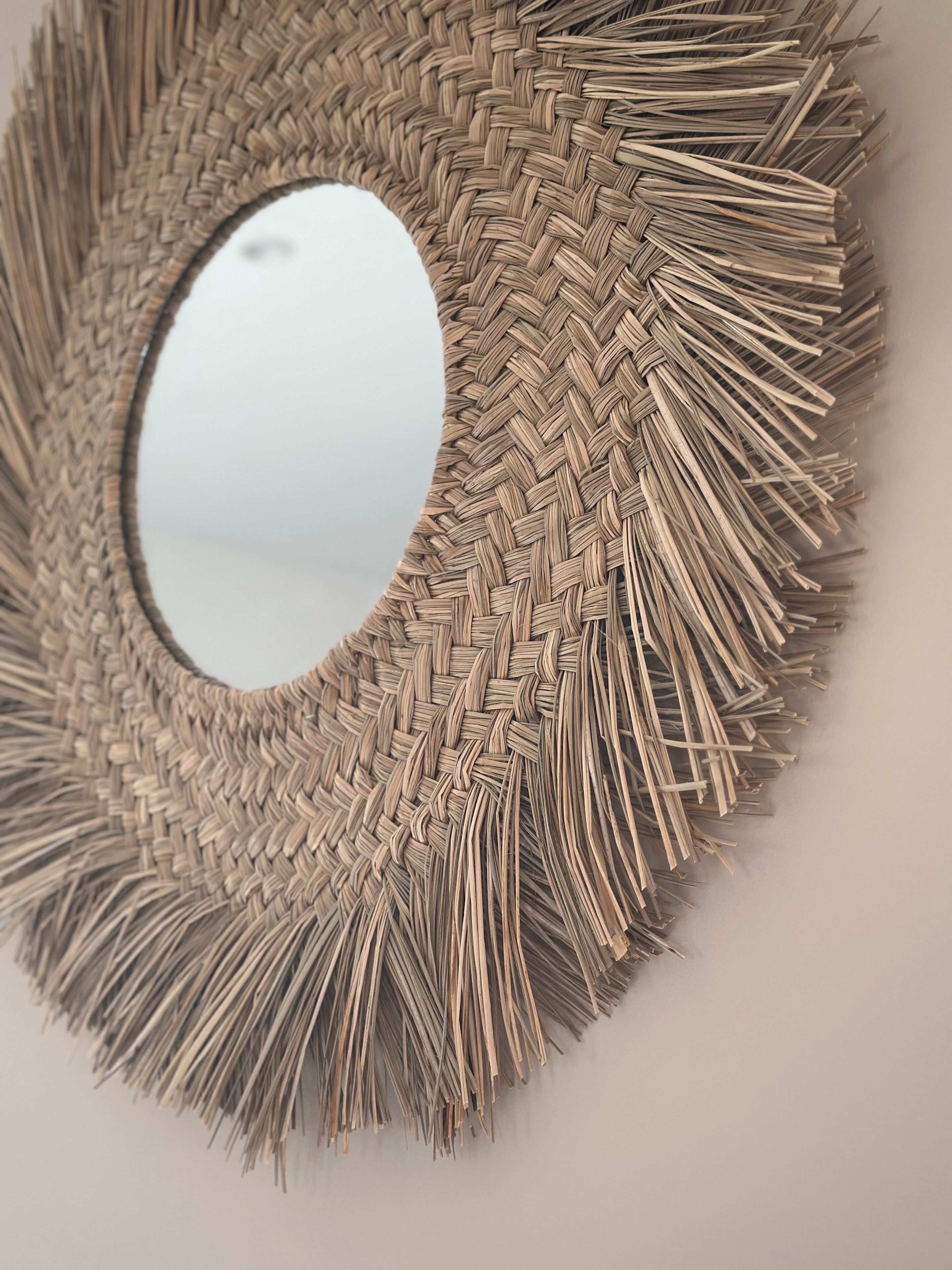 Un miroir rond, tissé, doté d’une surface réfléchissante.