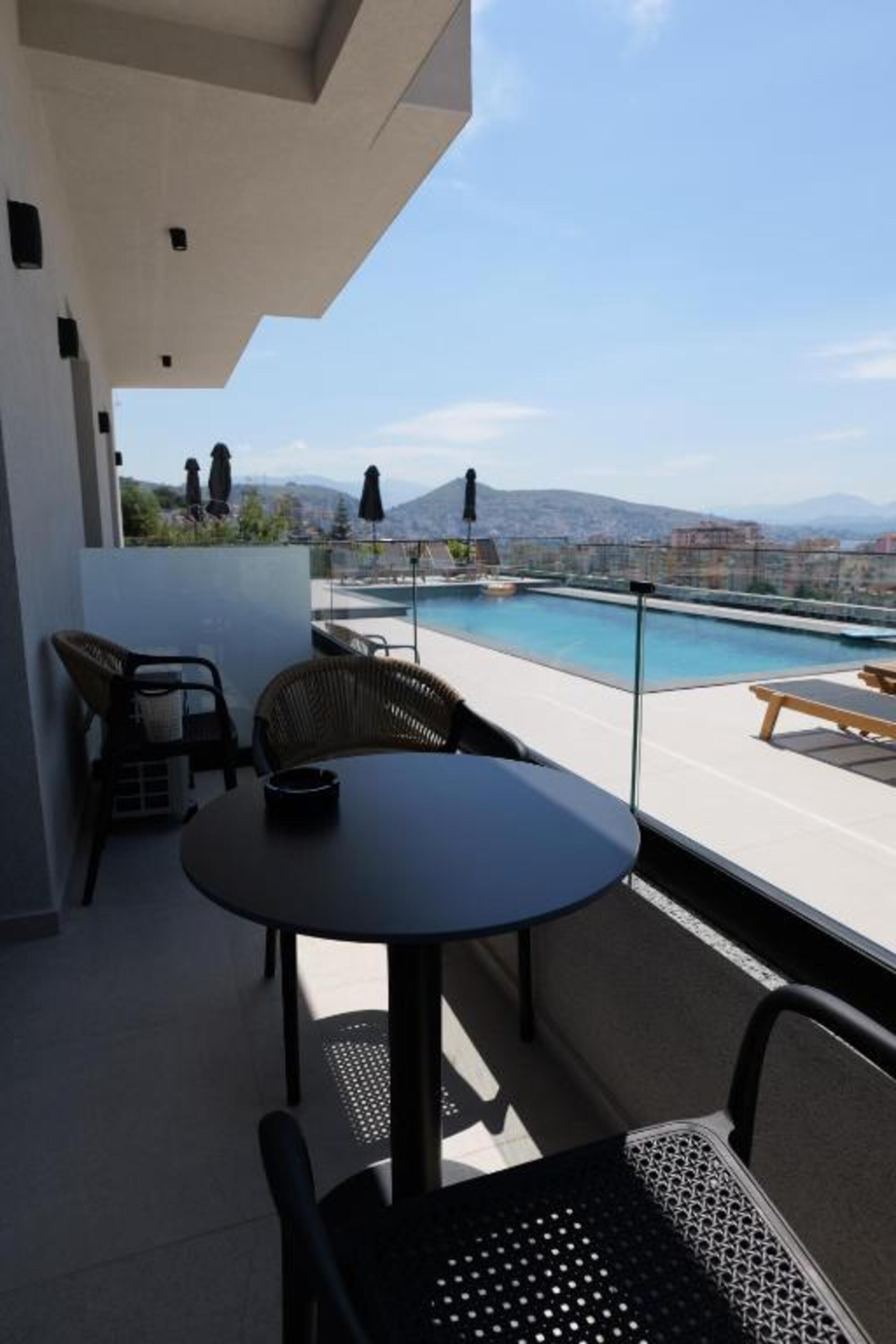Un balcon avec piscine, des meubles d’extérieur et une vue sur la ville.