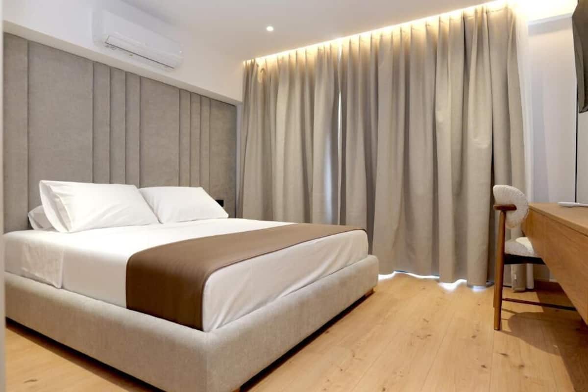Una habitación de hotel moderna con cama, escritorio y cortina.