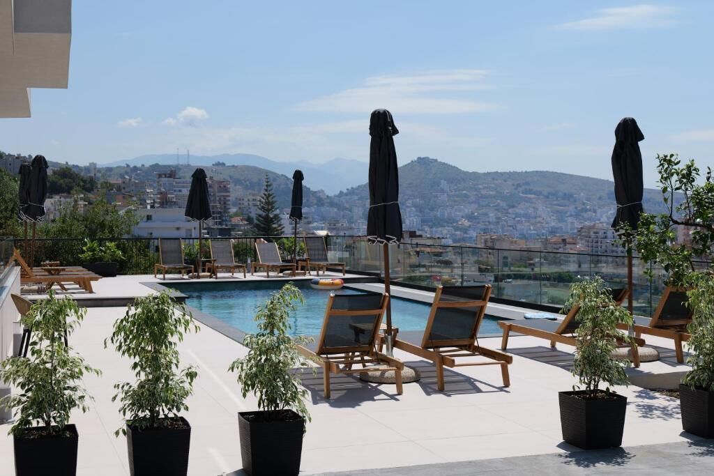 A rooftop pool area with lounge chairs and potted plants.