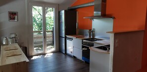 Eine Küche mit Herd, Backofen und Kühlschrank, einer Holzarbeitsplatte und einer Schiebetür zu einem Außenbereich.