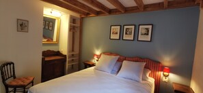 Ein Schlafzimmer mit einem Bett, einem Holzstuhl, einem Kleiderschrank, einem Spiegel und Wandleuchten.