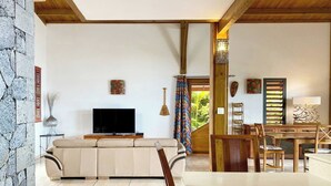 Een woonkamer met een bank, televisie en een eethoek met houten meubels.
