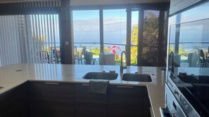 A modern kitchen with a large window, two sinks, and a view of the outdoors. - Villa TheOceane (Les Avirons)