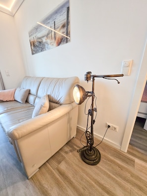 Ein modernes Wohnzimmer mit einer Couch, einer Vintage-Lampe und einem Bild an der Wand.