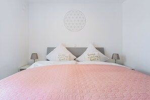 Ein Schlafzimmer mit einem Bett, Kissen, Wanddekoration und zwei Nachttischlampen.