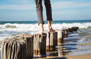 A person standing on wooden posts by the ocean.
