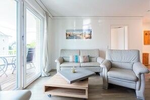 A modern living room with a sofa, armchair, coffee table, and a painting on the wall. - White Villa Grömitz apartment 11. sea view. Balcony. Close to the beach (Grömitz)