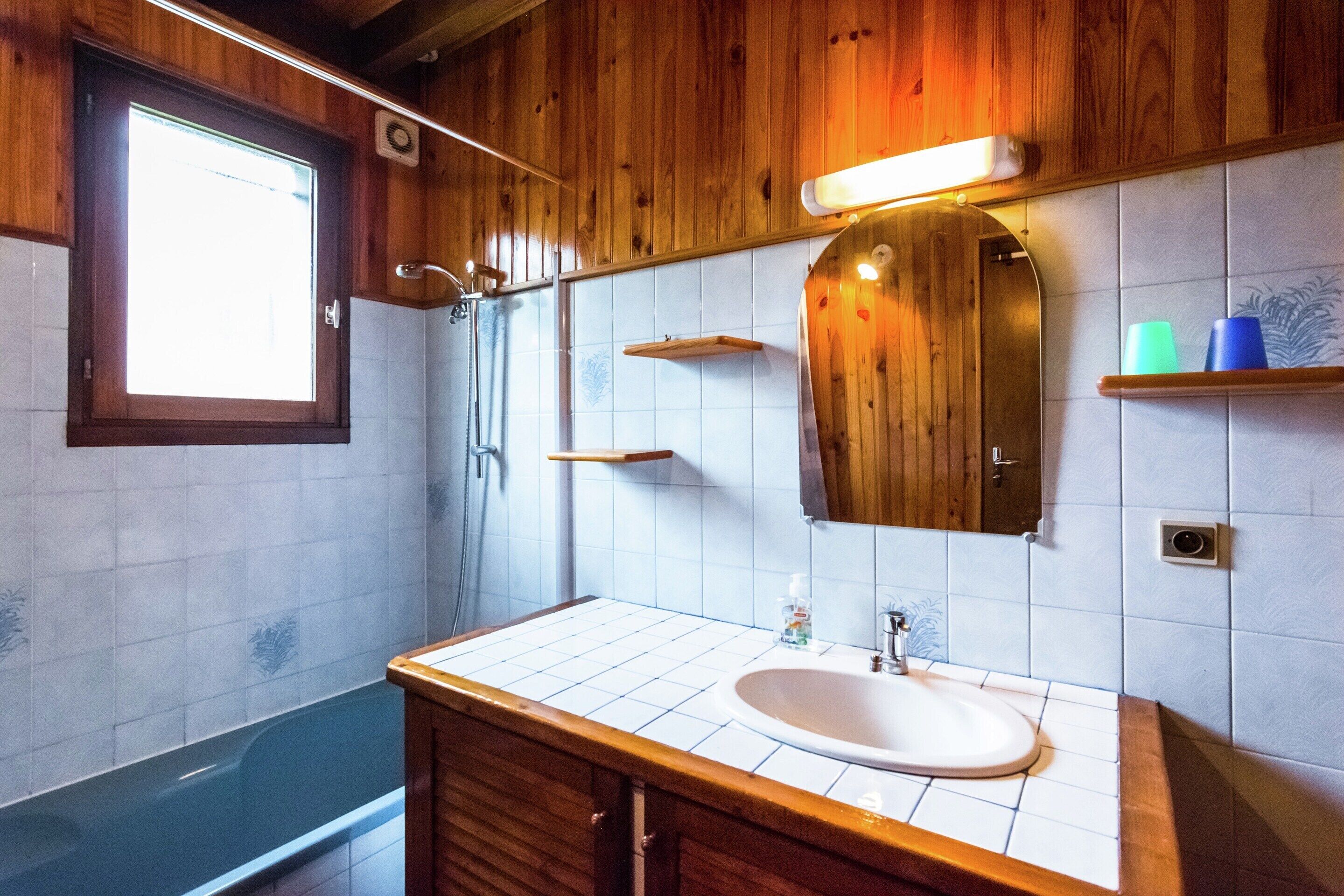 Un baño con tocador de madera, lavamanos, espejo y ducha.