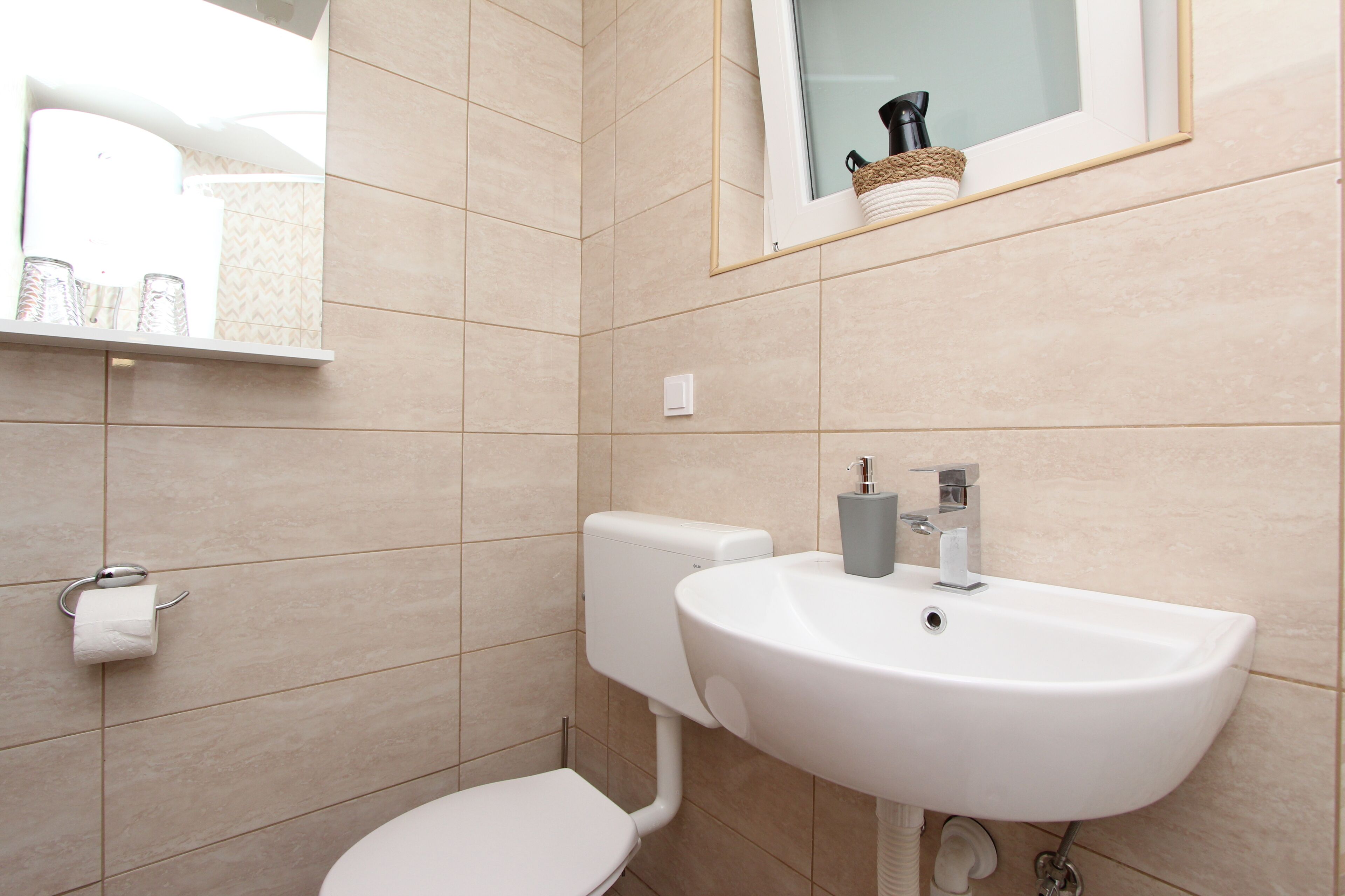 A bathroom with a toilet, sink, and mirror.