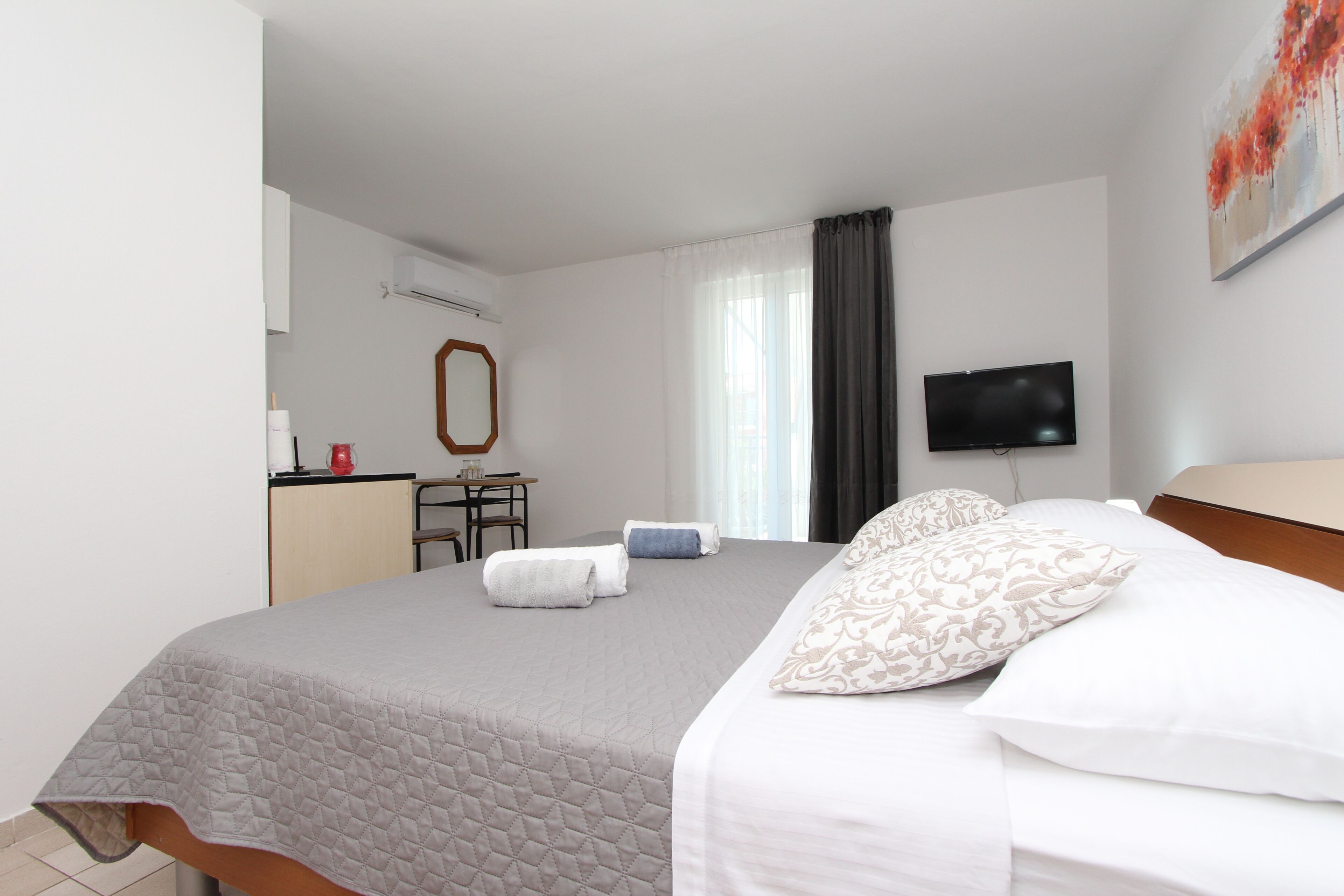 A hotel room with a bed, a desk, a chair, a television, and a window with curtains.