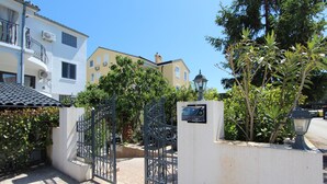A gated entrance with a sign, a lamp post, and buildings in the background. - Room and Studios Sole (Rovinj)