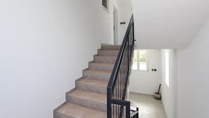 A staircase with beige steps and a black railing, leading to a room with white walls and a window. - Room and Studios Sole (Rovinj)