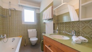 A bathroom with a bathtub, sink, toilet, and a window.