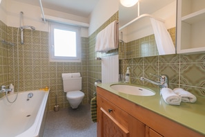 Ein Badezimmer mit Badewanne, Waschbecken, Toilette und einem Fenster.