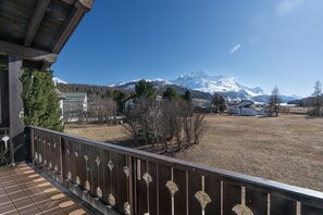 Ein Balkon mit Blick auf einen schneebedeckten Berg, einen Holenzaun und einen klaren Himmel.