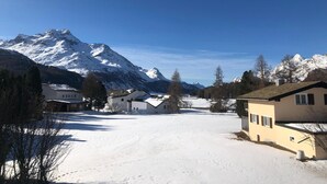A snow-covered village with houses and a mountain in the background.