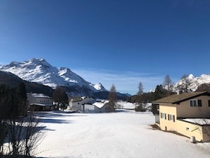 Ein schneebedecktes Dorf mit Häusern und einem Berg im Hintergrund.