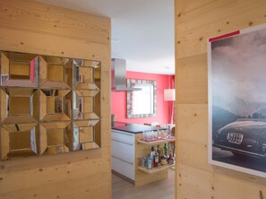 Ein Zimmer mit Holzwand, Spiegel, roter Wand, Fenster und einem Poster.