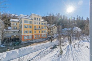 Ein mehrstöckiges Gebäude mit Balkonen, eine verschneite Straße und ein klarer Himmel.