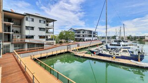Un puerto deportivo con barcos amarrados, una cubierta de madera y edificios modernos con balcones.