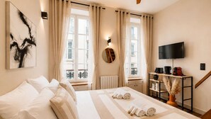 Ein Hotelzimmer mit Bett, Fernseher, Kaffeemaschine und Blick auf die Stadt.