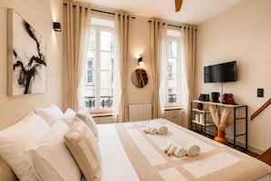 A hotel room with a bed, a TV, a coffee machine, and a view of the city. - Renovated studio with mezzanine in Le Marais (Paris)