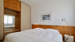 Une chambre à coucher avec un lit, une armoire en bois, une lampe de chevet et un tableau encadré au mur.