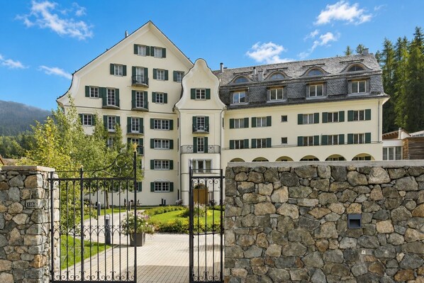 Ein großes, mehrstöckiges Gebäude mit steinernen Mauervorplätzen, einem gepflasterten Weg und einem gepflegten Garten.