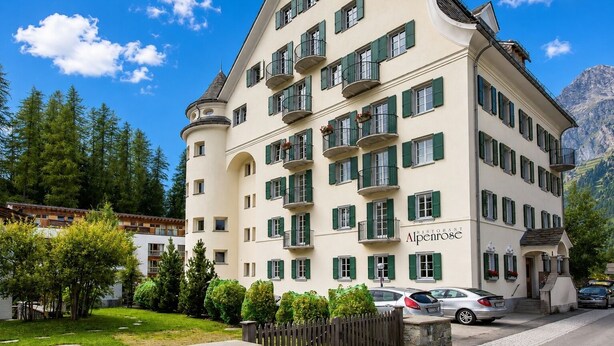 Un hôtel à plusieurs étages, de style architectural européen classique, doté de balcons et d’une enseigne de restaurant bien visible.